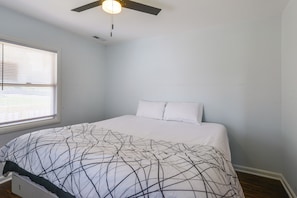 A bedroom with a bed, a ceiling fan, and a window with blinds.