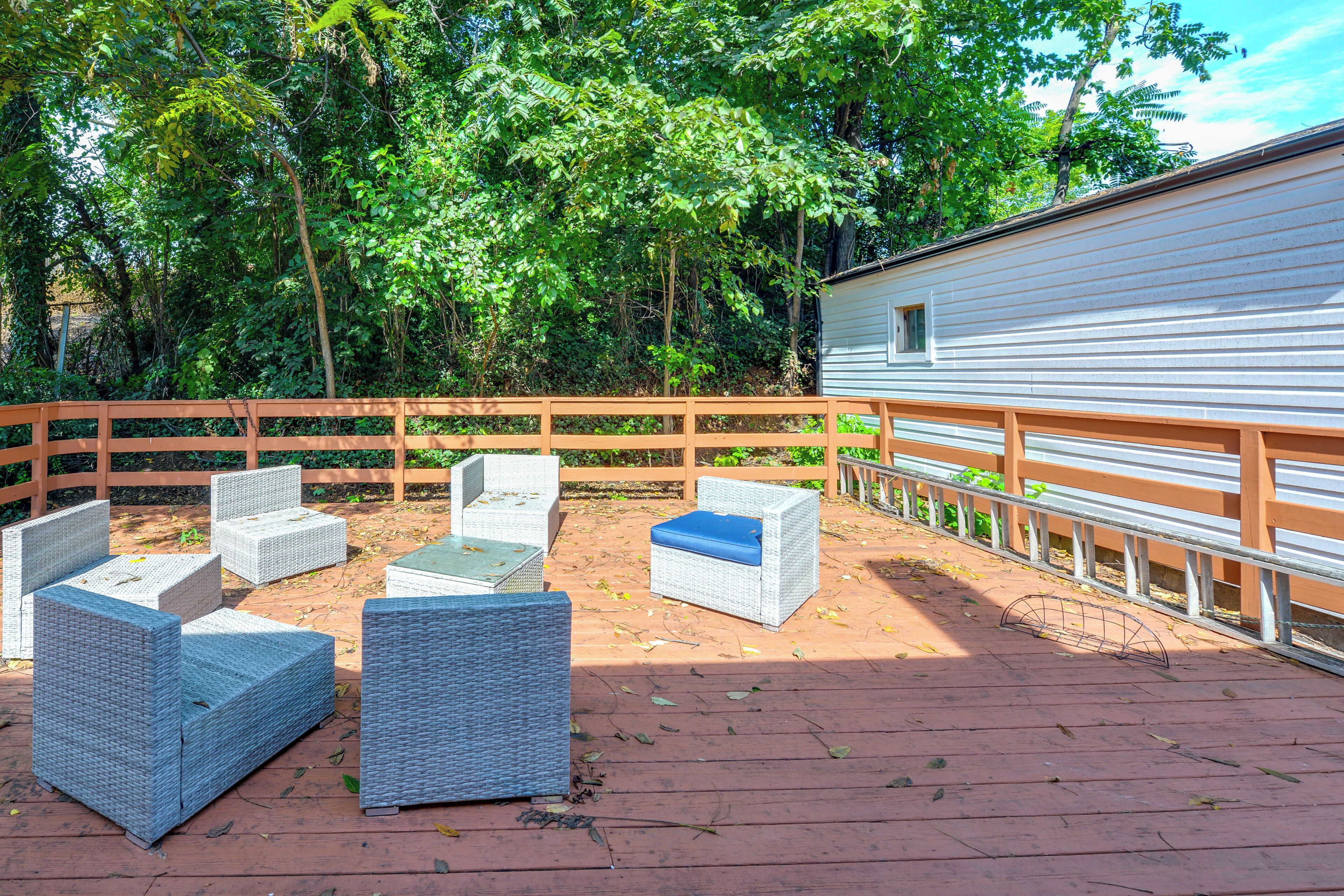 A covered outdoor seating area with wicker furniture and a wooden fence.