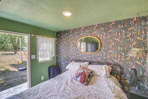 Une chambre à coucher avec un lit, un miroir, une fenêtre et une vue sur l’extérieur.