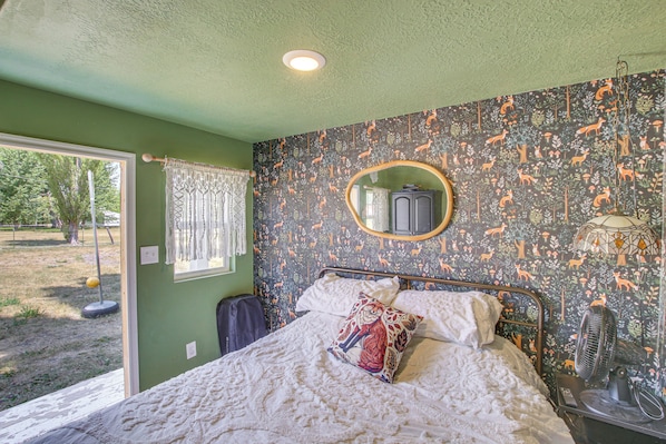 Un dormitorio con cama, espejo, ventana y vistas al exterior.