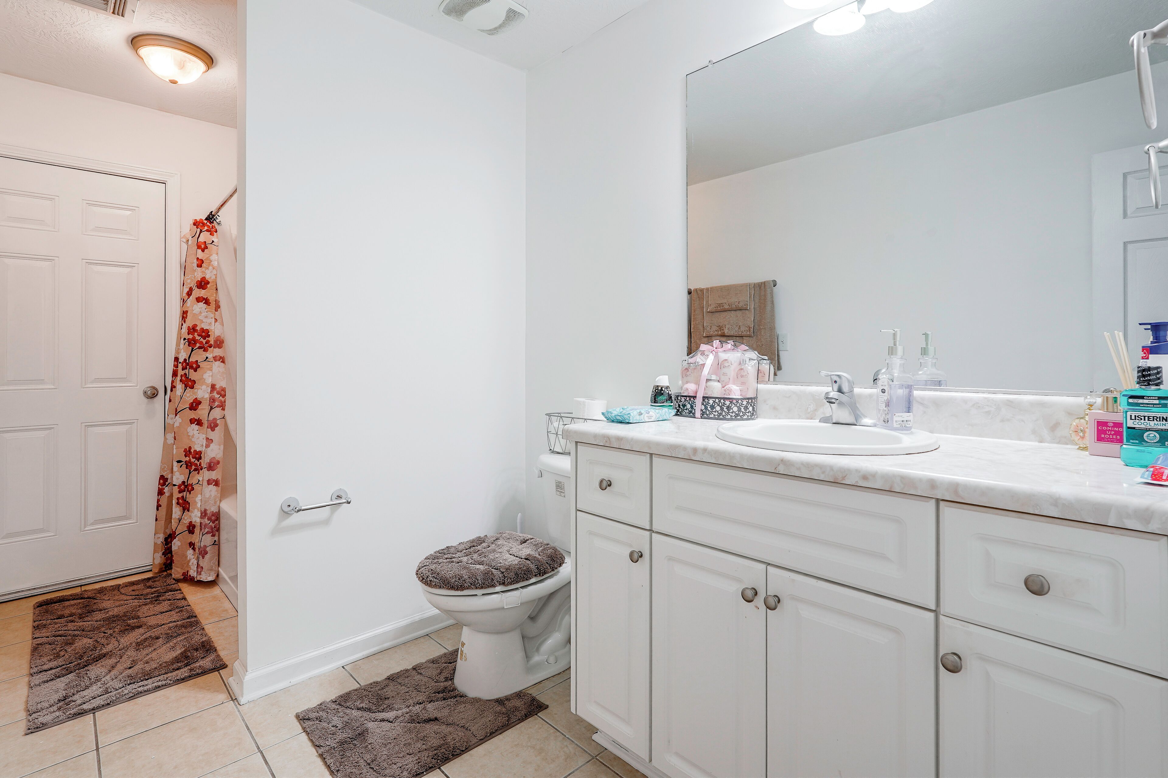 A bathroom with a toilet, sink, mirror, and a shower curtain.