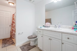 Un baño con inodoro, lavamanos, espejo y cortina de ducha.