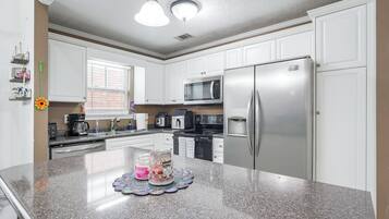 Una cocina moderna con armarios blancos, electrodomésticos de acero inoxidable y encimera de granito.