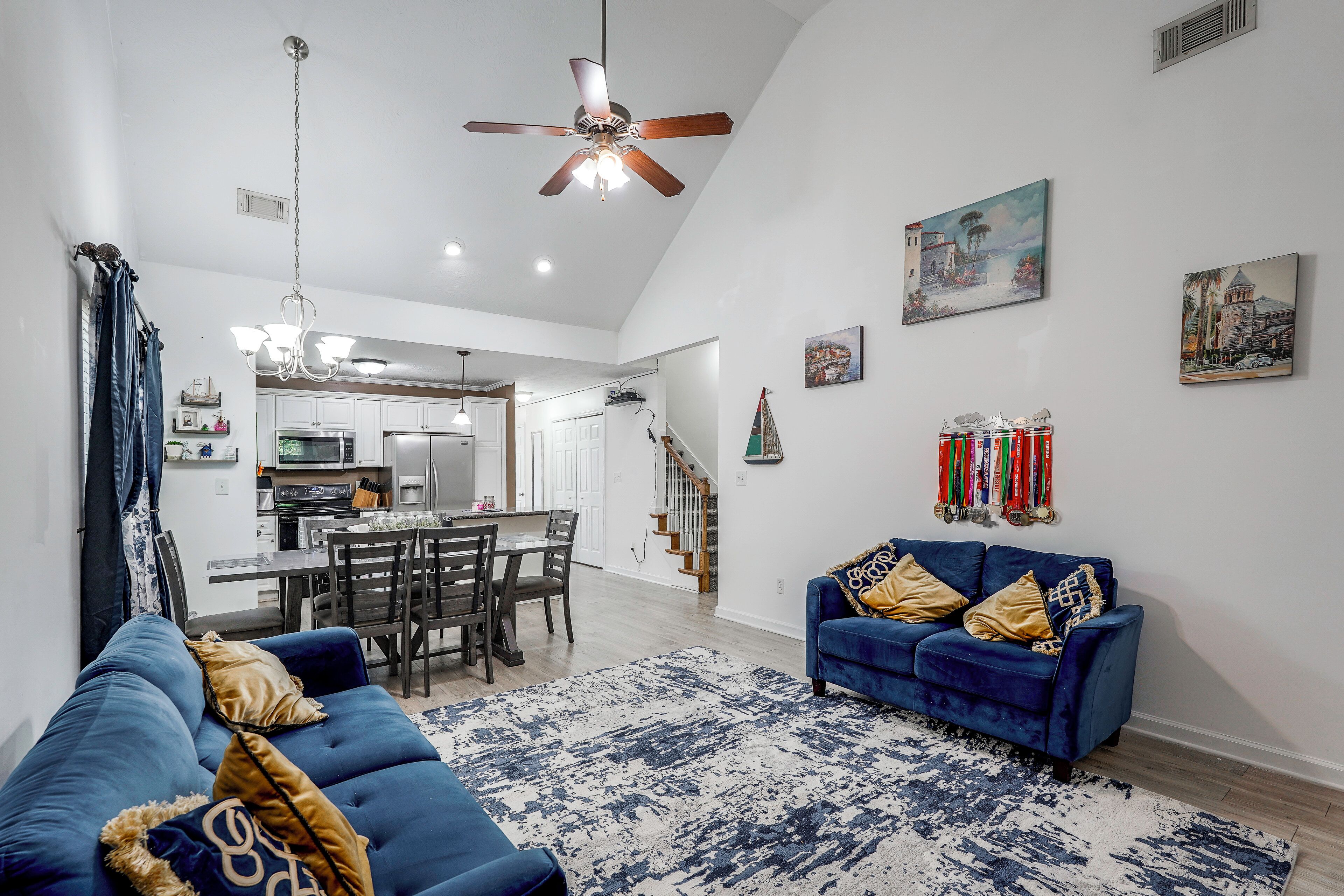 Amplia sala de estar con un sofá azul, una zona de comedor y una cocina al fondo.