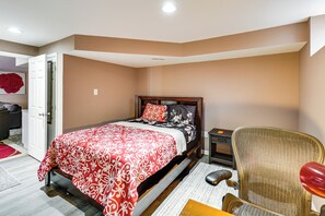 Um quarto com uma cama, uma cadeira, uma mesinha de cabeceira e uma porta.