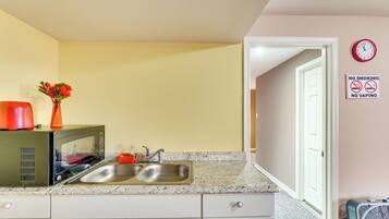 A kitchen with a double sink, a microwave, and a clock on the wall.