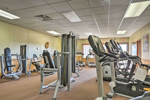 Uma academia com diversos equipamentos de exercícios, esteira e unidade de ar condicionado na parede.