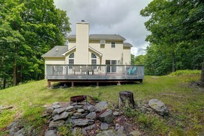 A two-story house with a balcony, surrounded by trees and a grassy area. - Poconos Getaway w/ Private Ski Slope & Pool Access (East Stroudsburg)