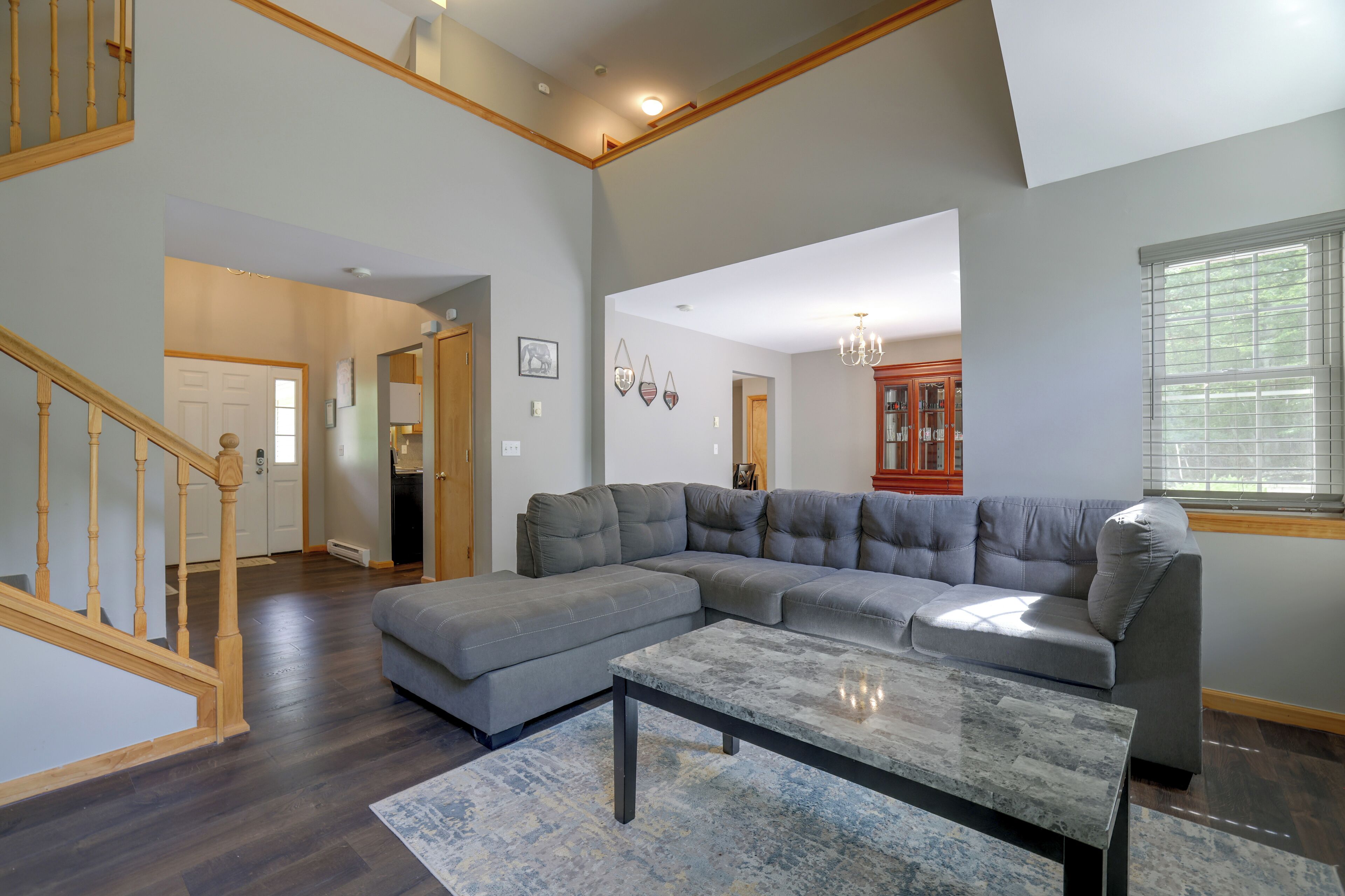 A spacious living room with a sectional sofa, a coffee table, and a staircase.