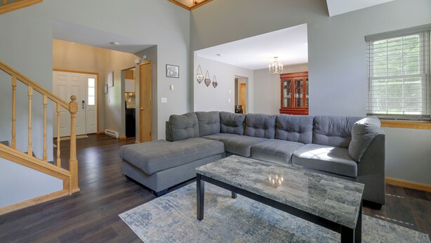 A spacious living room with a sectional sofa, a coffee table, and a staircase. - Poconos Getaway w/ Private Ski Slope & Pool Access (East Stroudsburg)