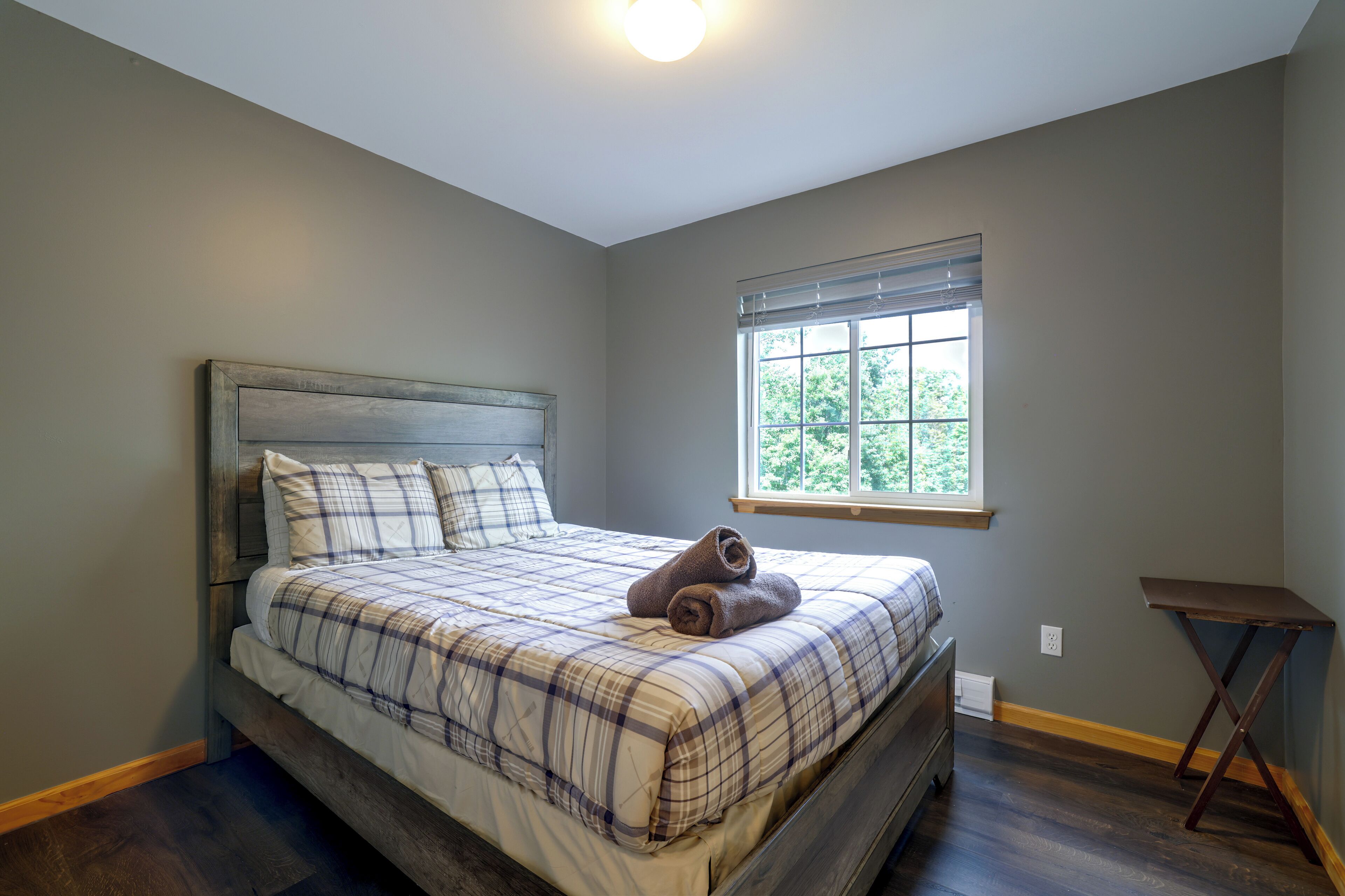 A bedroom with a bed, a window, and a small table.