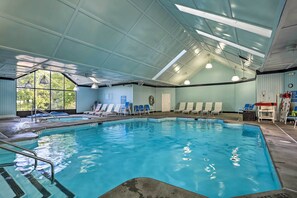 An indoor swimming pool with clear water, surrounded by lounge chairs and a covered roof structure. - Poconos Getaway w/ Private Ski Slope & Pool Access (East Stroudsburg)