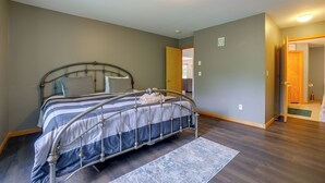 A bedroom with a metal-framed bed, a wooden door, and a view into another room. - Poconos Getaway w/ Private Ski Slope & Pool Access (East Stroudsburg)