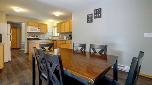 A spacious kitchen with wooden cabinets, a central island, and a dining table with chairs. - Poconos Getaway w/ Private Ski Slope & Pool Access (East Stroudsburg)