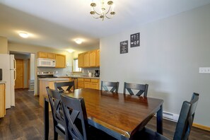 A spacious kitchen with wooden cabinets, a central island, and a dining table with chairs. - Poconos Getaway w/ Private Ski Slope & Pool Access (East Stroudsburg)