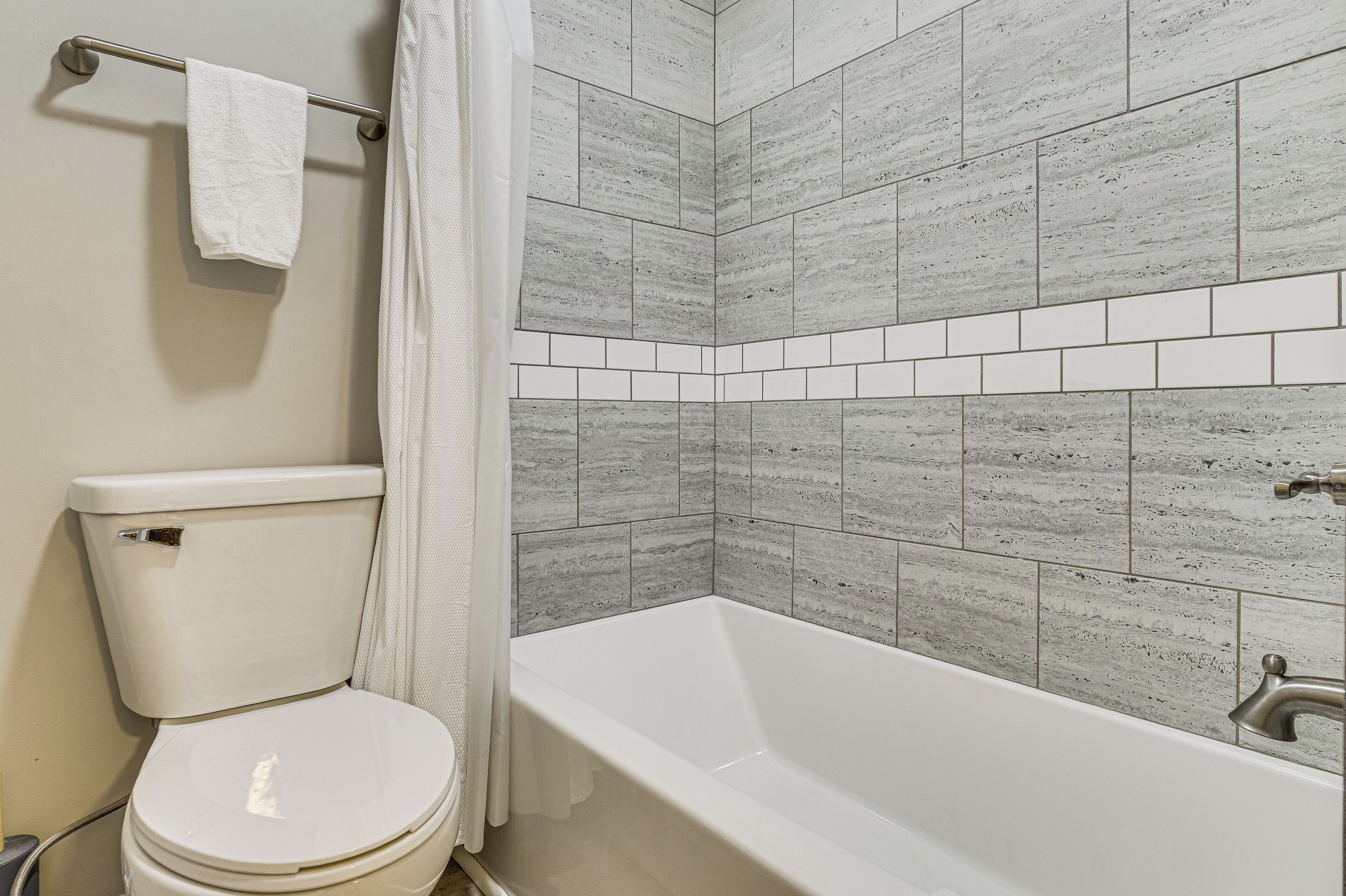 A bathroom with a toilet, a bathtub, and a shower curtain.