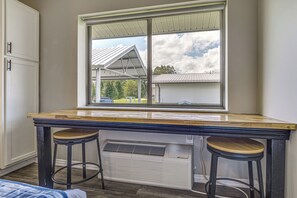 A room with a window, a table, two barstools, and a built-in air conditioning unit. - Golf, Fish & Explore: Updated Unit in Oakland City (Oakland City)