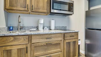 A kitchen with wooden cabinets, a built-in microwave, a coffee maker, and a stainless steel refrigerator.