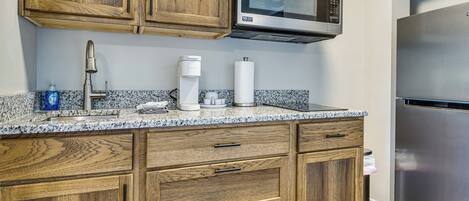 A kitchen with wooden cabinets, a built-in microwave, a coffee maker, and a stainless steel refrigerator.