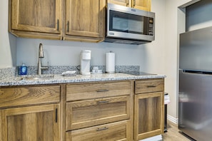 A kitchen with wooden cabinets, a built-in microwave, a coffee maker, and a stainless steel refrigerator.