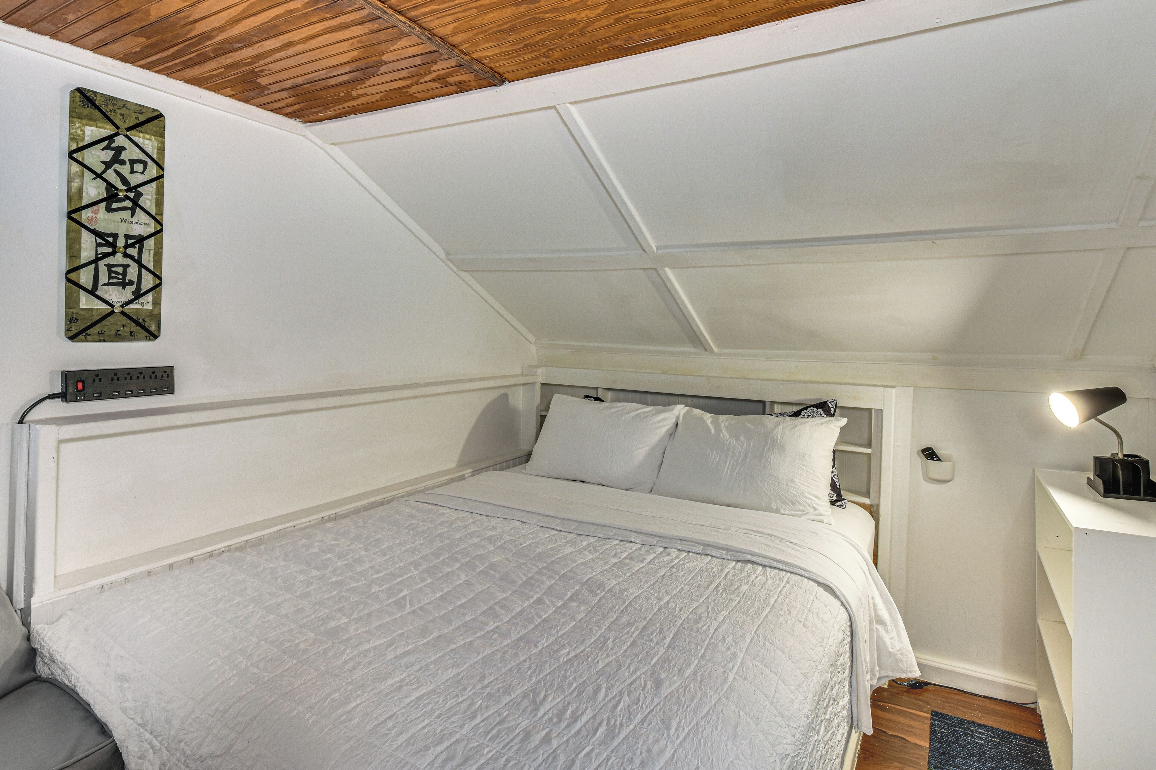 Un dormitorio con cama, mesita de noche con lámpara y decoración en la pared.