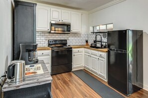 A compact kitchen with white cabinetry, a stainless steel refrigerator, a microwave, and a stove.