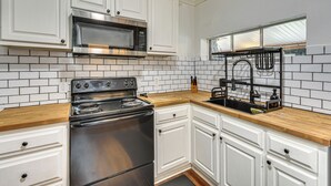 A kitchen with white cabinets, a stainless steel stove, a microwave, and a black faucet. - Hike, Fish & Explore! Family Getaway in Elberton (Elberton)