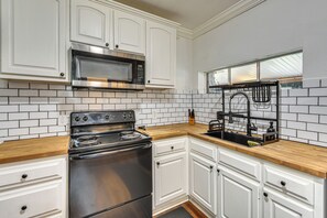 A kitchen with white cabinets, a stainless steel stove, a microwave, and a black faucet.