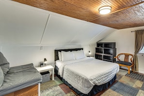 A bedroom with a bed, a nightstand, a chair, a bookshelf, and a window with curtains.