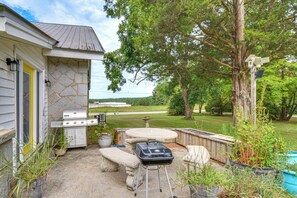 A backyard with a barbecue grill, outdoor seating, and a view of the surrounding landscape.