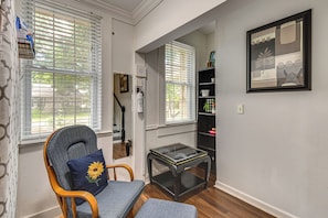 A room with a chair, a small table, and a bookshelf.