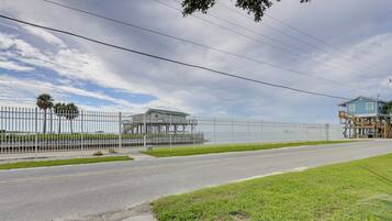 A fenced property with a road, grassy areas, and a blue building with a white roof.