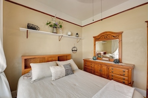 Un dormitorio con cama, cómoda y espejo.