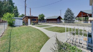 A residential area with a wooden cabin, a fenced yard, and a large evergreen tree.