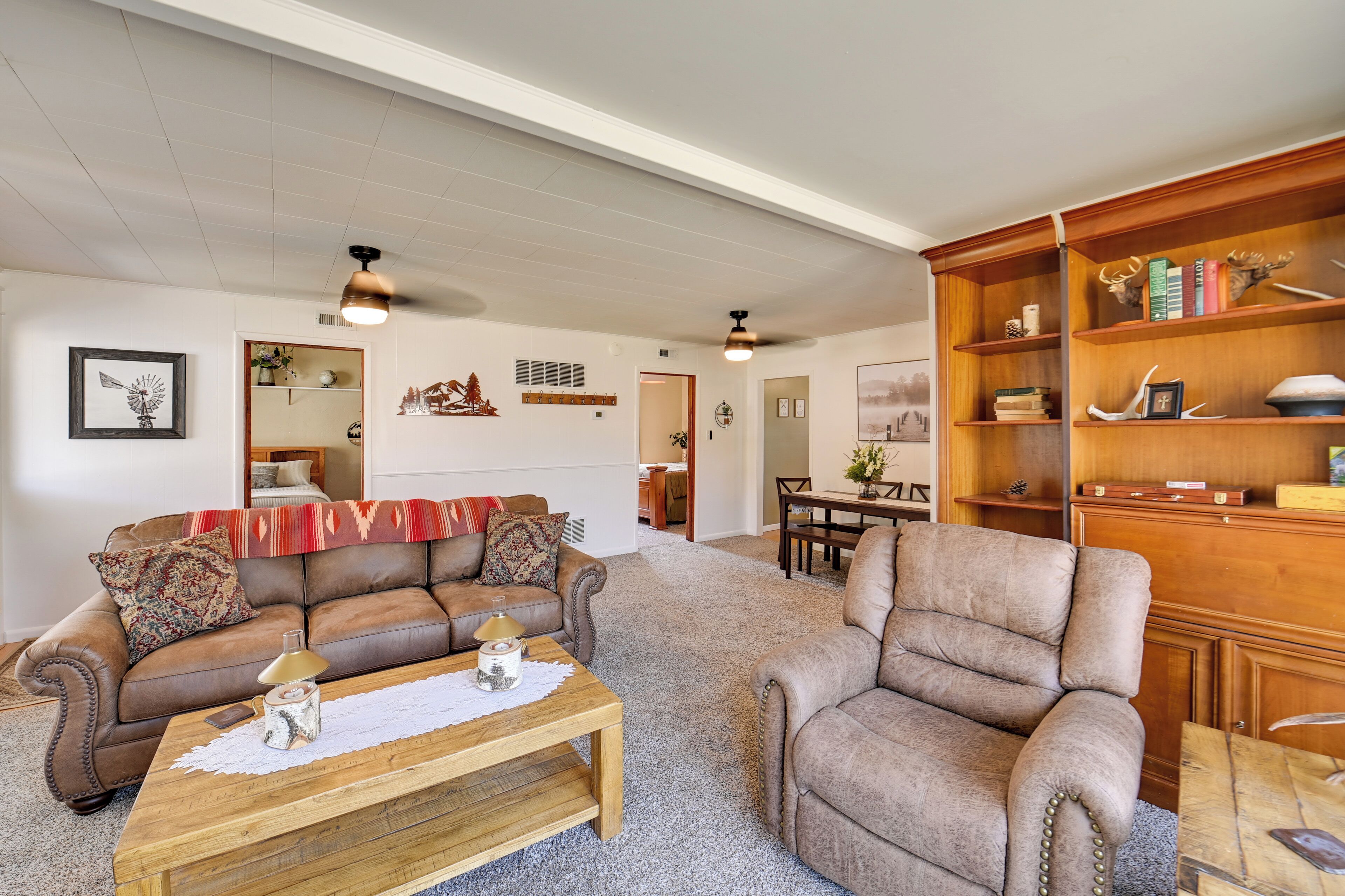 Una sala de estar con un sofá de cuero marrón, una mesa de centro de madera y una estantería.
