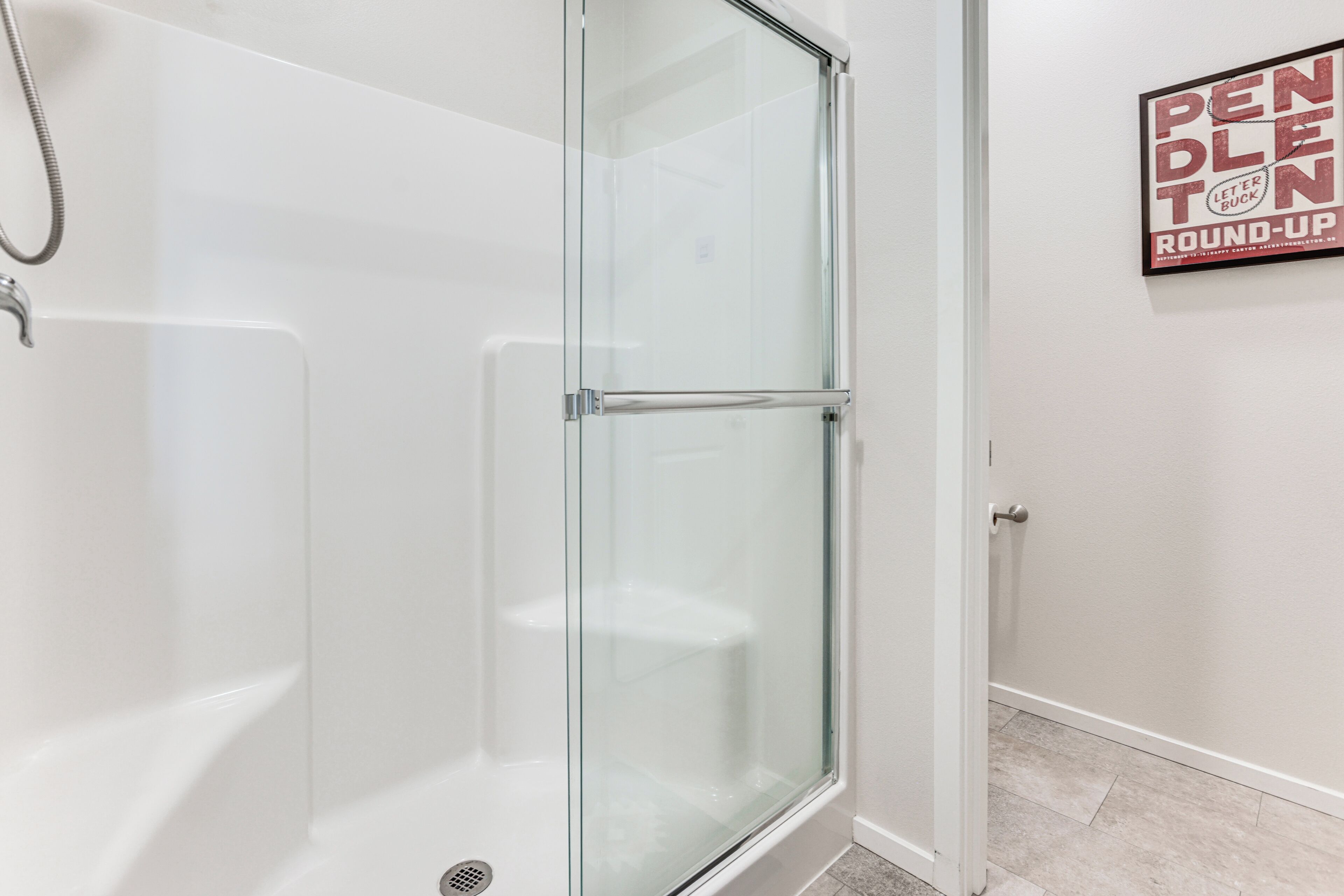 A modern bathroom with a glass shower enclosure, a white bathtub, and a wall-mounted towel rack.