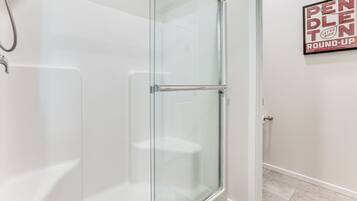 A modern bathroom with a glass shower enclosure, a white bathtub, and a wall-mounted towel rack.