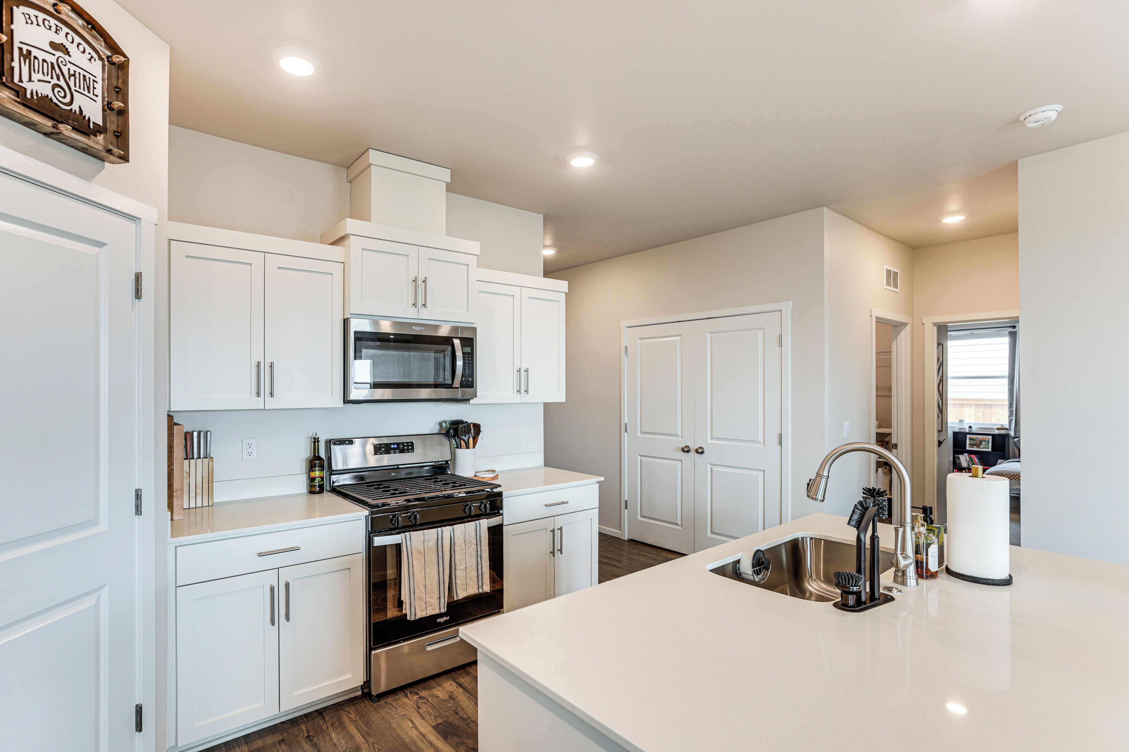 A modern kitchen with white cabinetry, a stainless steel stove, and a microwave.