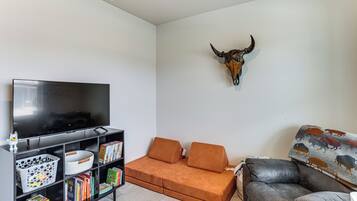 A living room with a flat-screen TV, a sofa, a patterned throw, and a wall-mounted bull's head.