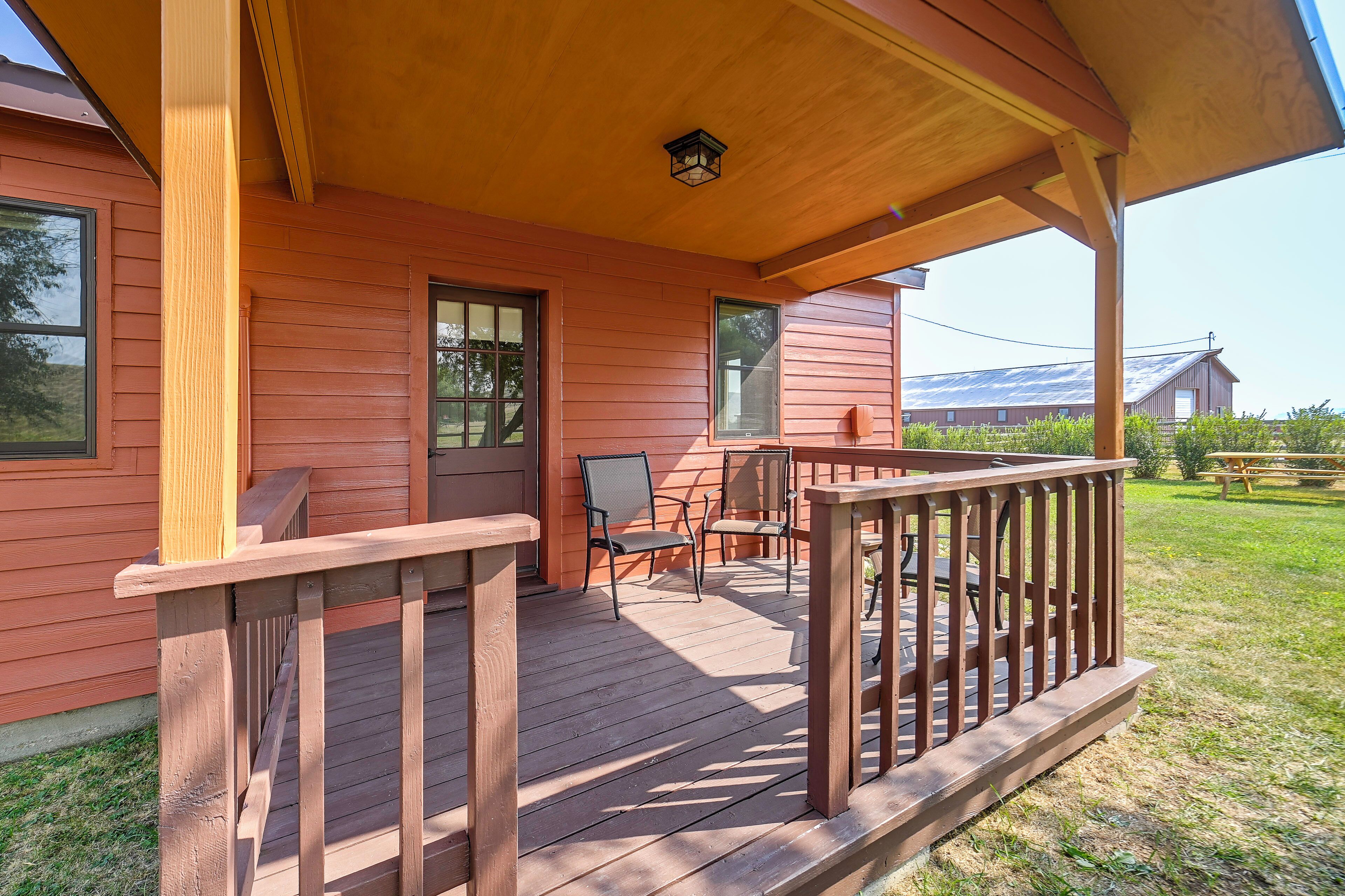 A wooden porch with a railing, a bench, and a chair.