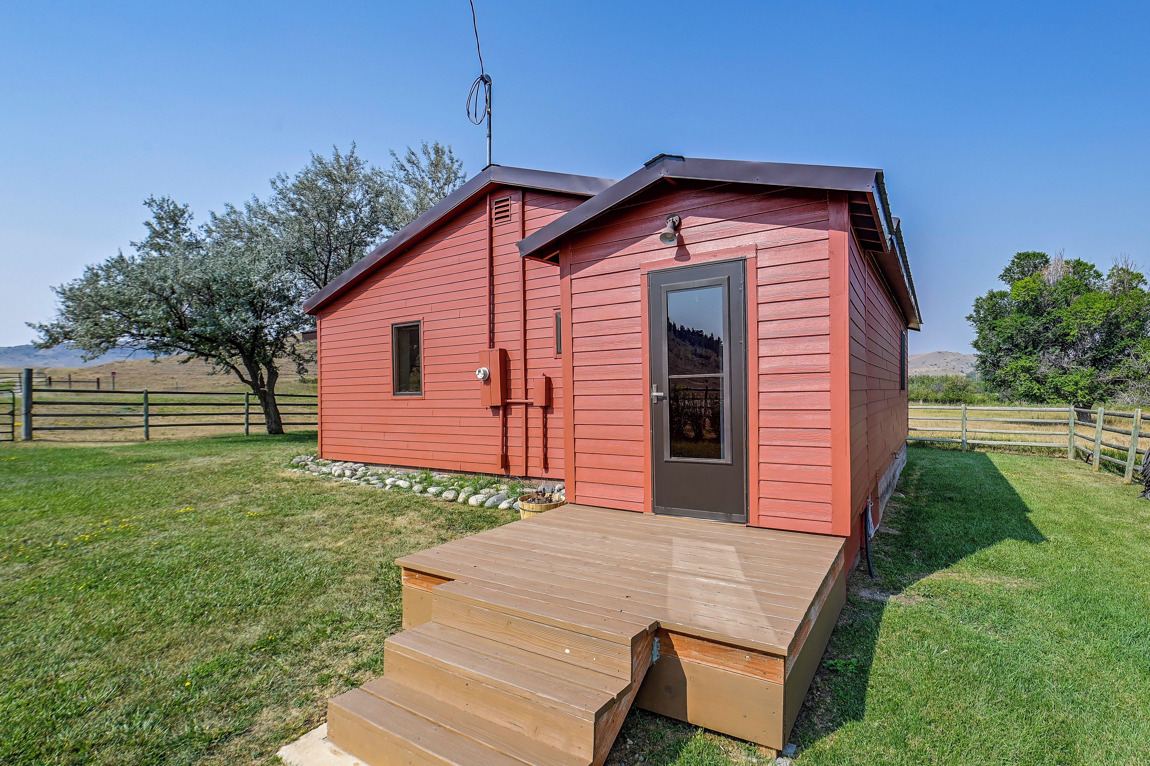 A red wooden cabin with a small porch and a door.