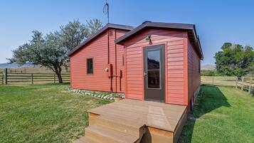 A red wooden cabin with a small porch and a door.
