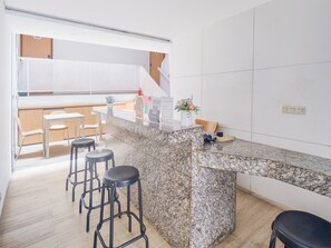 A modern kitchen with a granite countertop, bar stools, a small dining table, and a kitchen island. - Luxury Deluxe DBL Retreat W/ Free Wifi and Parking (Jakarta)
