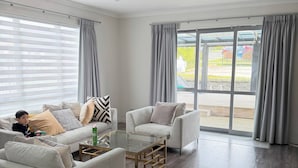 A modern living room with two sofas, a glass coffee table, and a large sliding glass door leading to an outdoor area.