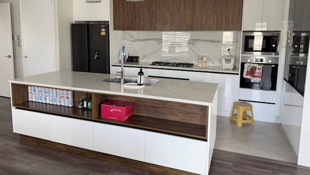A modern kitchen with a central island, built-in appliances, and a wooden accent wall.