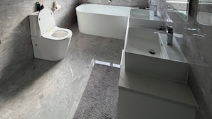 A modern bathroom with a toilet, bathtub, and sink.