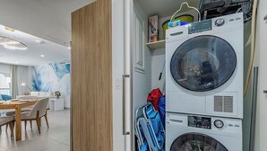 Un espacio habitable pequeño con comedor, lavadora y cochecito.