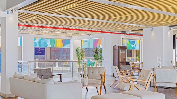 Un lobby moderno con techo de madera, asientos cómodos y grandes ventanales que ofrecen vistas al exterior.
