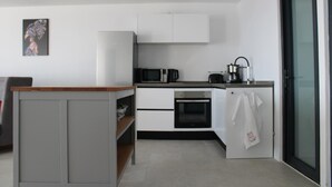 Uma cozinha moderna com armários brancos, micro-ondas, forno e uma geladeira pequena.