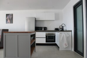 Eine moderne Küche mit weißen Schränken, einer Mikrowelle, einem Backofen und einem kleinen Kühlschrank.